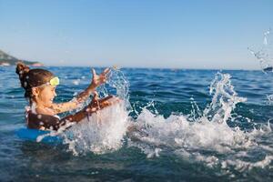 Cheerful girl sits in an inflatable circle and splashes with water in the sea photo