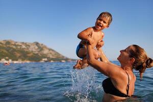 Cheerful mother plays with her son in the seaMother plays happily with son in seaMother and son play happily in the sea photo