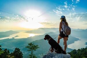 Hiker with dog overlooking mountain sunset photo
