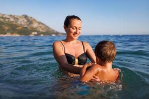 Cheerful mother plays with her son in the seaMother plays happily with son in seaMother plays happily with son in sea photo