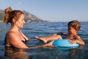 Caring mother rides her son on an inflatable ring in the seaCaring mother rides son inflatable ring seaMother rides son on inflatable ring in seaMother rides son on inflatable ring sea photo