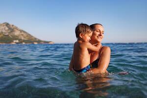 Cheerful mother plays with her son in the seaPlayful mother and son at sea photo