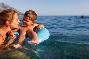 Caring mother rides her son on an inflatable ring in the seaMother rides son on inflatable ring sea photo