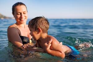 Cheerful mother plays with her son in the seaMother plays happily with son in seaCheerful mother plays with son in sea photo