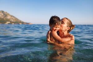 Cheerful mother plays with her son in the seaHappy mother plays with son at sea photo