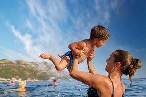 Cheerful mother plays with her son in the seaMother plays happily with son in seaMother happily plays with son in sea photo