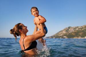 Cheerful mother plays with her son in the seaCheerful Mother Plays with Son SeaHappy mother and son playing in ocean photo