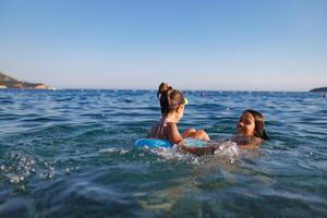 Two sisters in bathing suits play with an inflatable ring in the seaTwo sisters play with inflatable ring seaTwo sisters play with inflatable ring seaTwo sisters play with inflatable ring sea photo