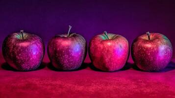 Four Red Apples Glowing Under Bold Purple and Pink Lights. photo