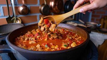 Georgian stew is being scooped from a clay pot with a wooden spoon, ready to be served. photo