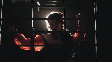 Woman posing behind bars in silhouette video