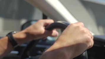 Close up of male hands gripping the steering wheel while driving a car, with bright sunlight in the background video