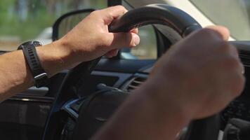 Close up of a male hands holding the steering wheel while driving, with a blurred outdoor background video