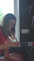 Woman in glasses sitting at desk and writing in notebook with focus and concentration video