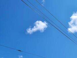 Blue sky background with trolley wires. Electric cables against a blue sky background. Transmission line cables. photo