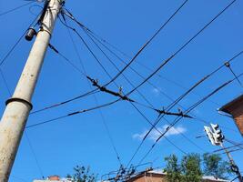 A pole with trolley wires against a blue sky. Electric power cables against a blue sky. Transmission line cables. photo