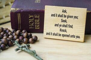 Ask, Seek and Know prayer text on wooden block with Holy Bible and Holy Rosary background. Christianity concept photo