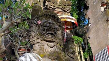 Traditional Balinese stone guardian statues at Hindu temple entrance in Bali, Indonesia. Sacred architecture with symbolic carvings and parasols. video
