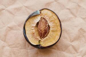 top view of dried plum slice isolated on brown paper texture background photo