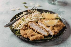 A photograph of a meticulously arranged plate featuring golden-brown chicken schnitzel photo