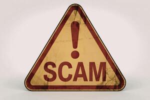 a warning sign with a word SCAM written in bold red capital letters photo