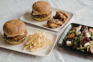 Burgers, fries, and salad on table photo