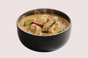 A photograph of a vibrant chicken curry served in a sleek black ceramic cup photo