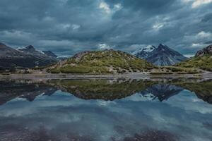 A photograph of a serene calm lake reflecting snow-capped mountain peaks photo