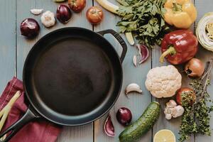 A pan with vegetables and other ingredients on a wooden table photo