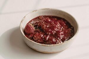 a ceramic bowl filled with glistening raspberry jam photo