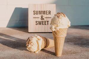 Two ice cream cones with a sign that says summer and sweet photo