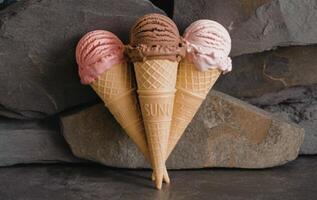Three ice cream cones with different flavors on a stone background photo