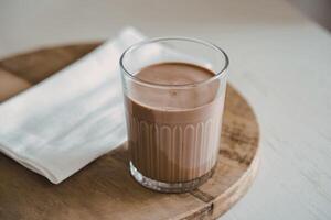 A photo of a clear glass filled with chocolate milk