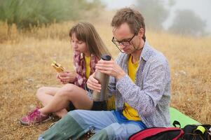 Couple Enjoying A Picnic Break in Nature While Hiking Through a Grassland Area photo