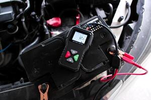 Car battery being tested with a battery tester, vehicle maintenance with diagnostic tool. photo
