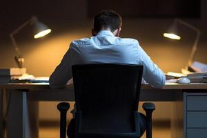 Person working late at night at a desk with focused lighting. Fatigue ,physical and burnout syndrome concept. photo