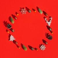 Christmas round frame with natural decorations, wooden toys, pine cone on red Winter celebration concept. photo