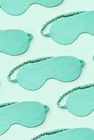 Minimal pattern from silk sleep masks. Turquoise colored eye masks for best sleepers, for travel, comfort rest. Sleep well concept. Creative aesthetic top view, flat lay monochrome pattern photo