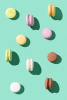Pattern from different cake macaroons on bright blue green color background, multi colored french biscuit macarons. photo