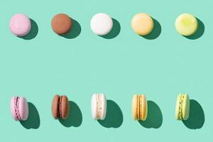 Assorted macaroons on bright blue green colored background, colorful french cookies macarons. photo
