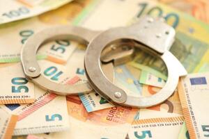 Police handcuffs lies on a set of monetary denominations of euros photo