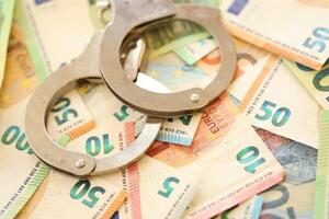 Police handcuffs lies on set of green monetary denominations of euros photo