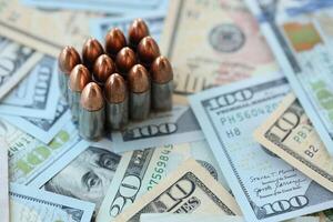 Pistol bullets and cartridges lies on many dollar bills photo