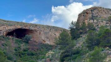 A cave in the mountains with trees and bushes video