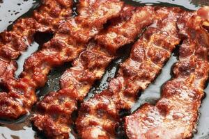 Bacon slice being cooked in a frying pan photo