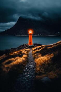 Light From the Lighthouse Guides Ships Along the Rugged Coast Under Dark Skies. photo