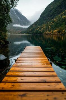 Serene Wooden Dock Extending Into a Calm Fjord Surrounded by Mountains Under a Cloudy Sky. photo