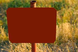 Red frame for text on an old pipe in a field with dry grass photo