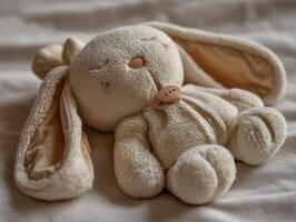 Soft rabbit plush toy resting on a bed. photo