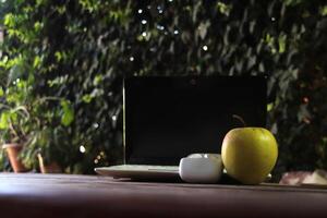 The theme of training, freelancing, education. On the table there is a white laptop and wireless headphones. A green apple indicates a snack photo